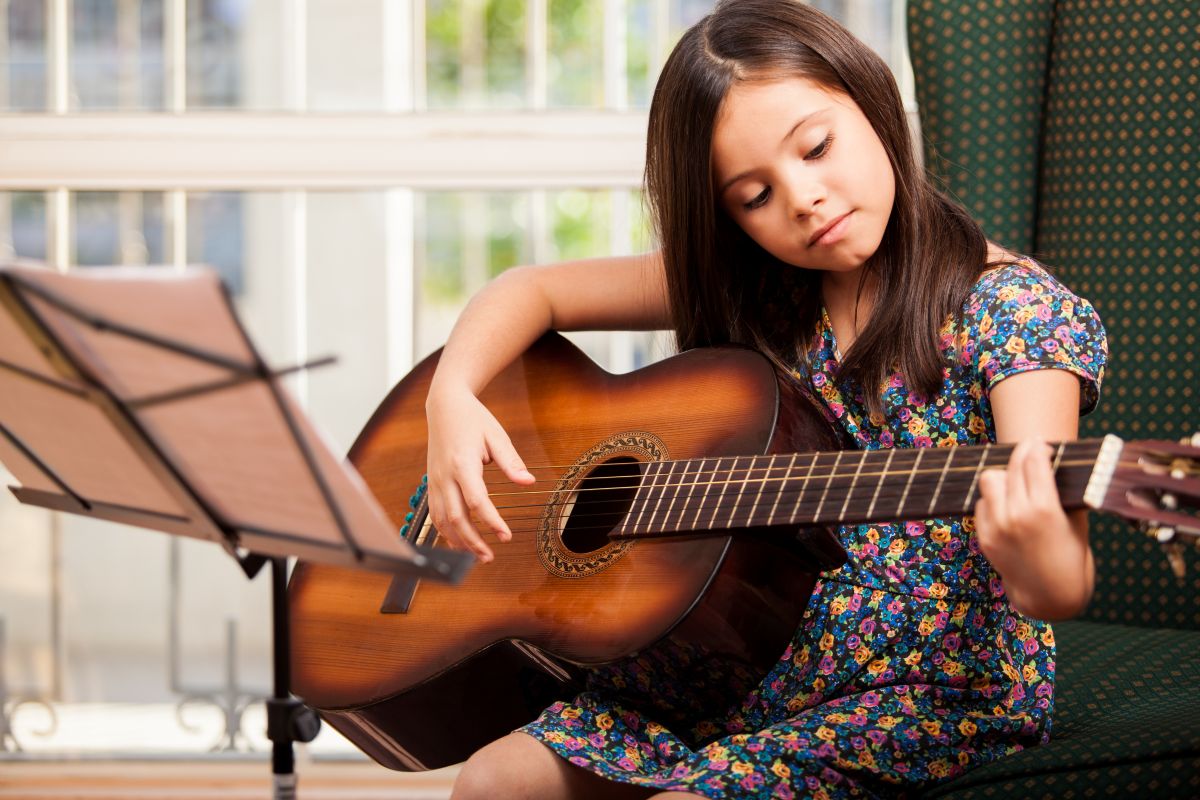 A female child playing Guitar looking at the chords
